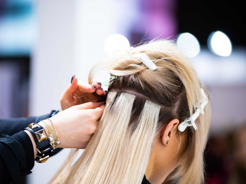 How Do Clip In Hair Extensions Work? A Beginner’s Guide 6 Clip in hair extensions being applied to blonde hair in a salon