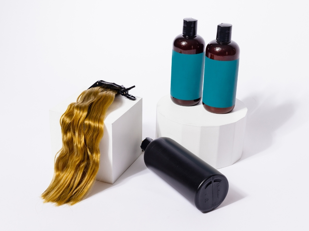 How Do Clip In Hair Extensions Work? A Beginner’s Guide 9 Blonde wavy hair extension with shampoo and conditioner bottles