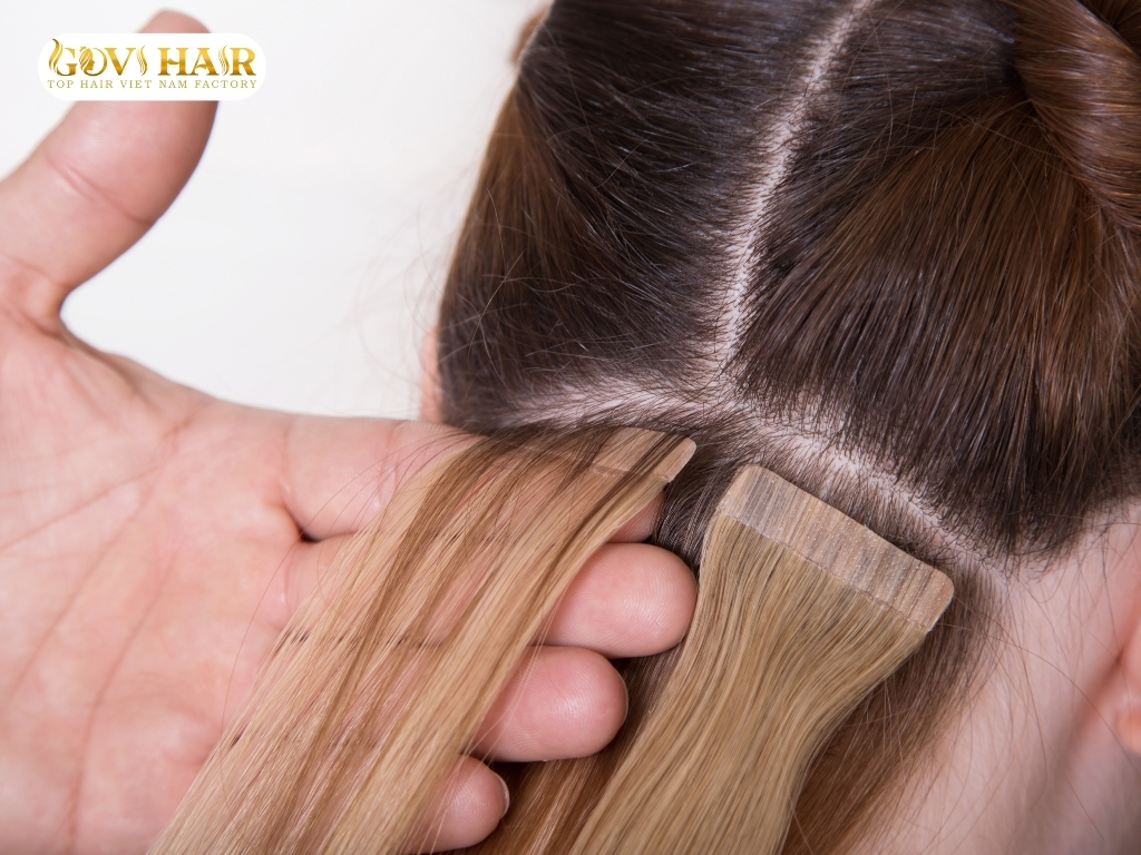 Stylist applying tape-in hair extensions to natural hair to enhance length and volume.