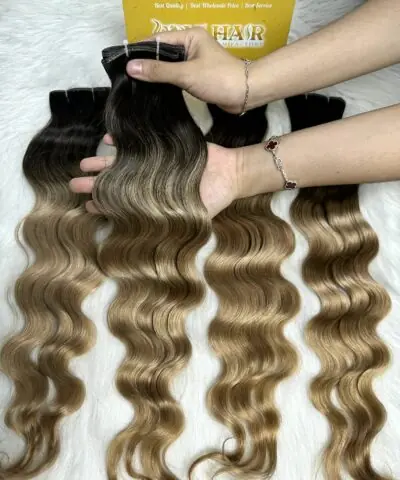 Wavy genius weft extensions ombre blonde held by hand