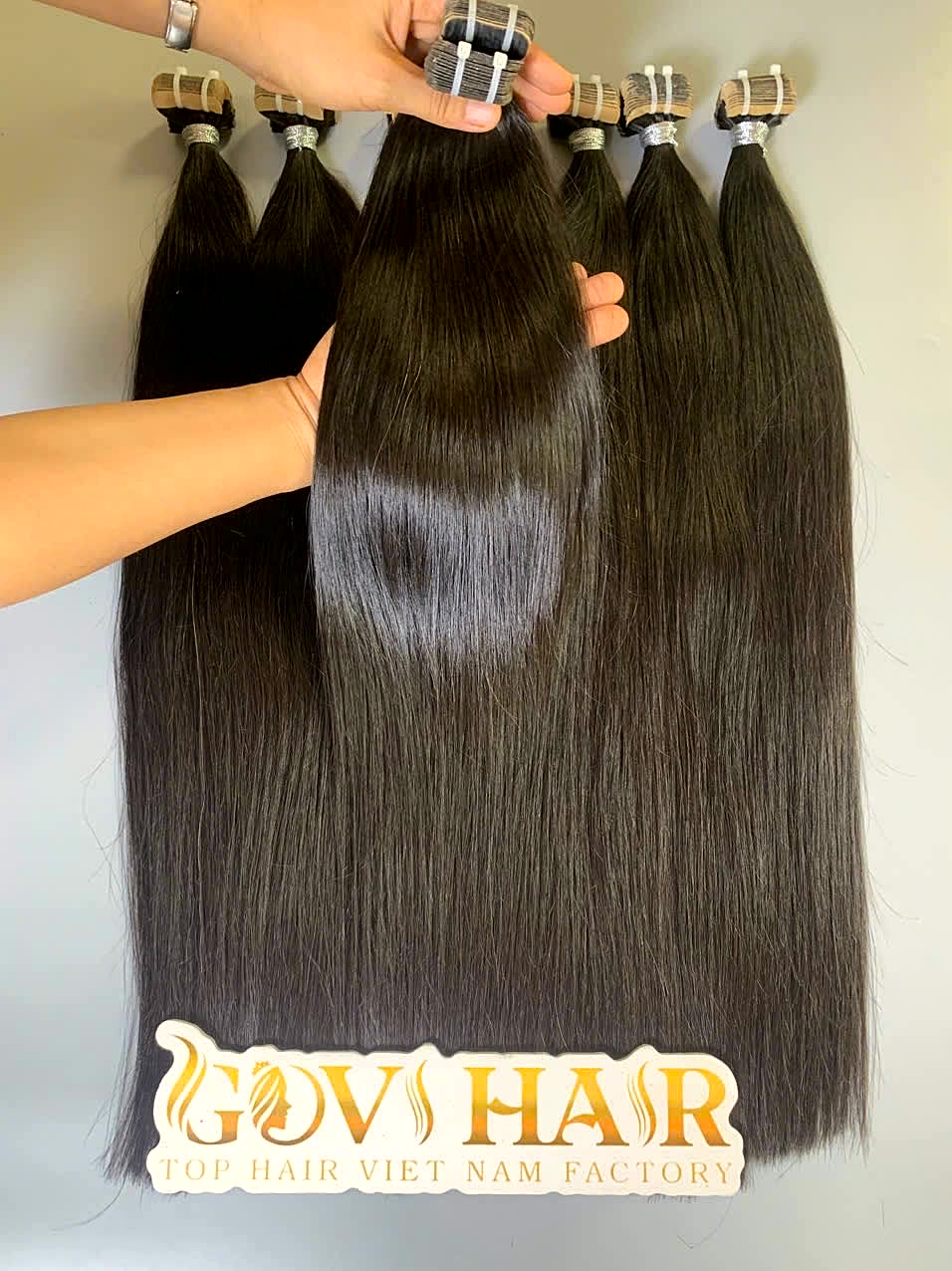 24 Inch Raw Vietnamese Tape In Hair Extensions Natural Straight Wholesale 1 raw tape in hair extensions held by hand showing shine