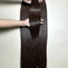 raw hair bundles in natural brown held by hand showing shine