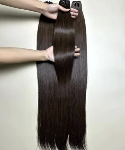 raw hair bundles in natural brown held by hand showing shine