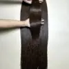 raw hair bundles in natural brown held by hand showing shine