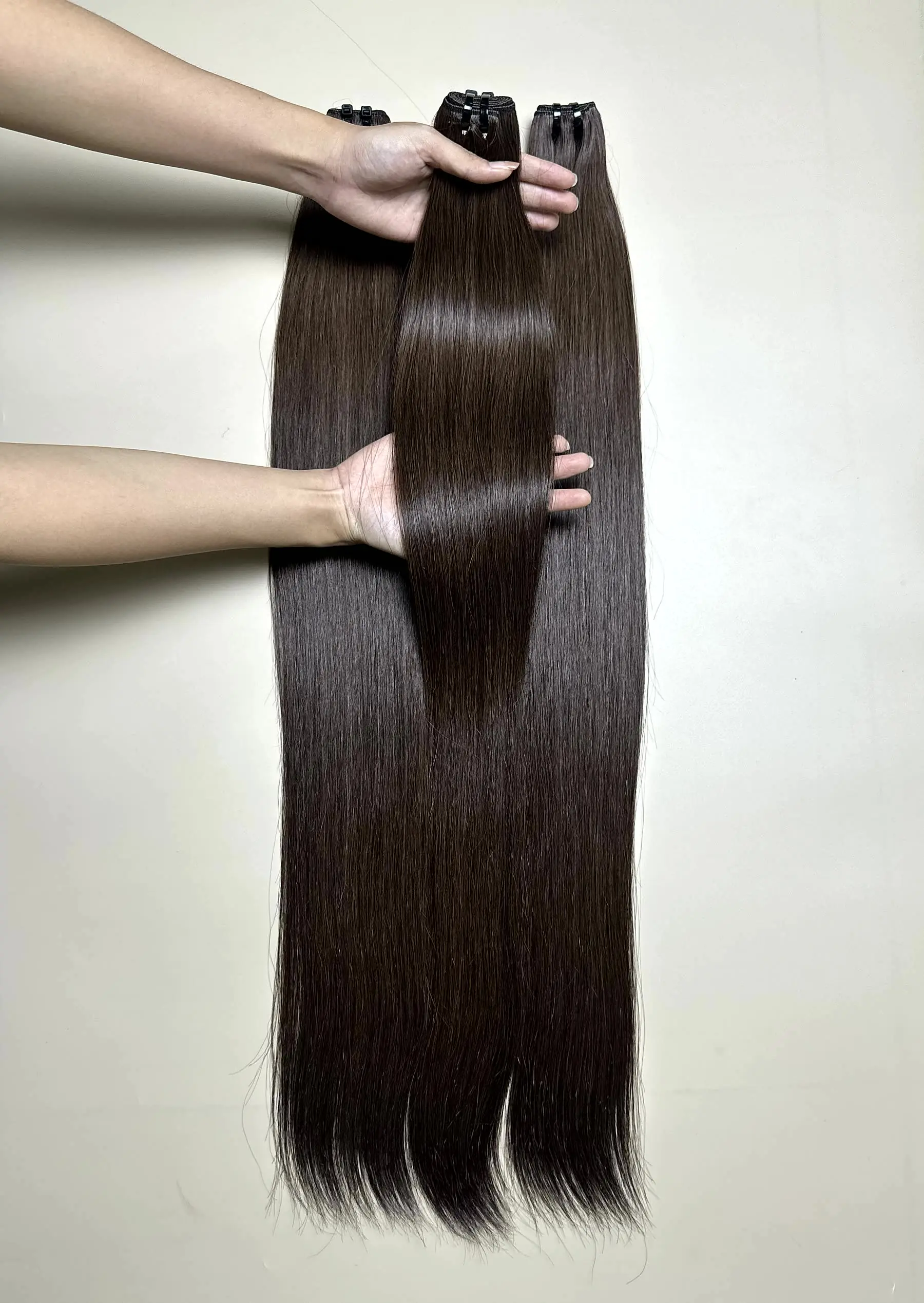 raw hair bundles in natural brown held by hand showing shine